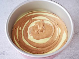 16、斑马纹戚风蛋糕,就这样一勺原味一勺可可，直至所有的蛋糕糊用完，端起模具的两端，轻轻震几下，震出大气泡