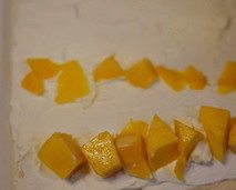 11、芒果烫面蛋糕卷,出炉连烤盘在台面上从上往下大力震一下,震出热气,然后连同烘焙纸将蛋糕片移在烤架上降温,等待蛋糕体降温的时候重新拿一张新的油纸,盖在蛋糕体上面,以免蛋糕体干掉。