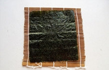 4、紫菜包饭,将海苔片铺在寿司专用的竹帘上。