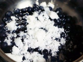 2、蓝莓果酱,砂糖平分为两份，先倒一半糖进去，中火，用勺搅拌。