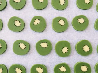 12、抹茶猕猴桃小饼干,用少量黑芝麻装饰，技巧是一手拿牙签蘸水再粘黑芝麻，另一只手也拿着牙签做辅助，把黑芝麻摆放好。考验耐心的时刻哦～