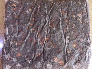 13、枣泥核桃糖,按照枣泥核桃糖的边缘，把烘焙纸折成，方形，用擀面杖把纸包糖团擀平