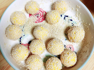 12、南瓜芝麻球,撒上一些白芝麻，将南瓜球在盘中转起来，均匀的沾满白芝麻。