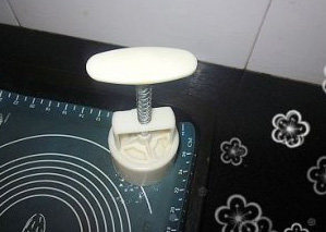 11、木糖醇广式莲蓉月饼,模具洒上适量干粉，敲去多余的粉，将月饼坯放进去，放在烤盘上，用点力压出花纹，压出来