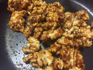 14、蜂蜜核桃仁,翻拌均匀,尽量使每个核桃仁都裹上糖浆,你也就可以此时撒入熟白芝麻,我们家孩子一般不喜欢吃芝麻故没放