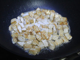 5、孜然小葱煎豆腐,待豆腐煎至金黄色时，掂几次锅让豆腐煎的更均匀些。