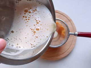 11、太阳果虾皮蛋羹-辅食,将加了温水的蛋液过筛倒入太阳果盅里,用勺子撇去表面浮沫