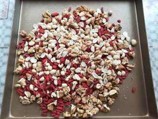 3、核桃花生芝麻糖,把花生和枸杞一起放到烤盘里备用