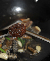 6、酱烧黄鳝,倒入一汤匙料酒和一茶匙豆瓣酱翻炒均匀。
