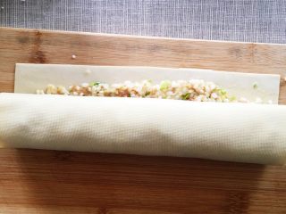 4、千张糯米肉卷,从一个边卷起来，要卷的紧一些，封口处涂抹水淀粉，把有封口的面朝下放入蒸笼里大约20分钟左右。
