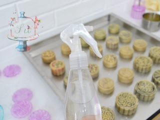 13、预拌粉版快手广式月饼,月饼全部按压好脱模之后,准备一个喷雾很细的喷壶。从高处薄薄的喷一层水雾在刚刚脱模好的月饼坯上。这样可以防止开裂。送入预热好的烤箱中层,温度转