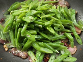 12、四季豆炒腊肠,倒入四季豆翻炒,让四季豆吸收一点腊肠的油。