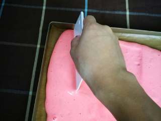 10、织女也疯狂 — 【爱心蛋糕卷】,将烫面戚风蛋糕糊倒在画满爱心的烤盘上,用塑料刮板将表面抹平,注意塑料刮板千万不要探底。