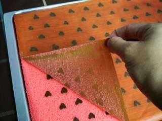 12、织女也疯狂 — 【爱心蛋糕卷】,将戚风蛋糕倒在铺油纸的烤盘上,撕去表面油纸,换一张新油纸,再倒扣过来,爱心面朝下。