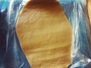 15、迷你芒果挞,在面团上下各放一个保鲜膜，隔着保鲜膜将面团擀开。