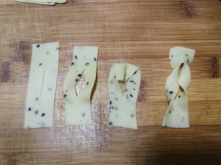 12、年味～花式炸麻叶,2指宽的长条再切成约5cm长的小段，用刀从中间切一下，然后如图将上部面片从中间的切口穿进去再拉出，2指宽的麻叶整形就做好了