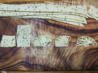 16、年味～花式炸麻叶,这是4指宽面片做成扇形的整形方法，把4指宽面片对折后切成10～12股，展开后左上角对右下角按紧，然后右上角也慢慢收拢与右下角右侧部分重合按紧，最后左下角也慢慢收拢与右下角左侧部分重合按紧，稍微整理一下就成为扇子一样了