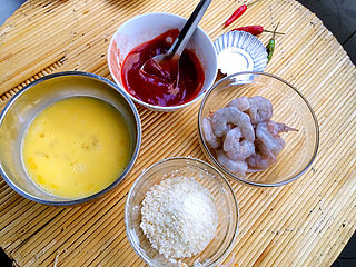 3、番茄香酥虾球,将番茄酱倒入到碗里,加入少量矿泉水、白砂糖、米醋进行调稀,备用!鸡蛋放入碗里,搅拌均匀,备用!面包糠放入碗里备用