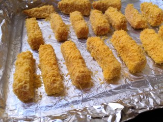 12、十味   香酥南瓜条,把裹好面包糠的南瓜条，放在刷有油的锡纸上。