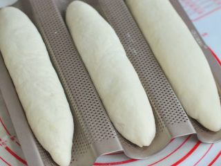 11、葡萄干麻糬软欧,将面团左右捏合住，整形成长条状，放在法棍模上。