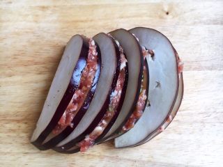 15、香炸茄子盒,将调好的肉靡夹在茄子片里，刮去周边多余的肉靡。