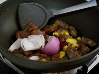 4、土豆烧牛肉,5.当水分差不多炒出时,将备好的调料除西红柿和小葱都放入锅中,继续保持中小火炒。