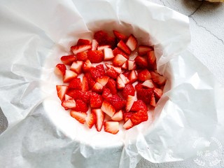 3、草莓炒酸奶+南瓜芋圆水果捞,找一个平底模具,然后铺一层油纸,把草莓颗粒放进去。