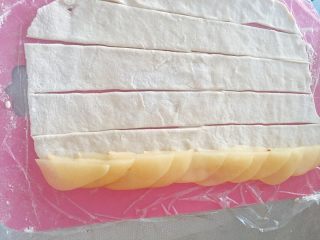 5、玫瑰苹果塔～,取出冷却的熟苹果片，按照如图方式摆放，苹果切边占面条宽的1/3，大概1cm左右。注意：苹果片不要重叠太密集。