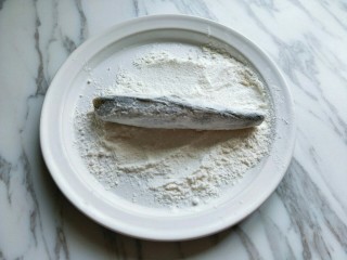 8、#做妈妈的拿手菜#红烧冰鱼段,取一块大一点的盘子，放上上午面粉，将腌制好的冰鱼段，放入面粉中，裹上面粉，最后在抖掉多余的面粉。