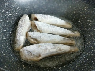 9、#做妈妈的拿手菜#红烧冰鱼段,起油锅，加入适量食用油，放入裹上面粉的南极冰鱼段。