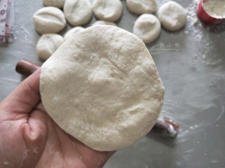 12、香菇青菜包子--不一样的做法,切好后多撒点手粉，按扁擀皮。一手提着点皮，一手拿擀面杖擀，边擀边转皮。包子皮不用擀很薄很大，手掌大小就行，擀成中间厚旁边薄的皮。