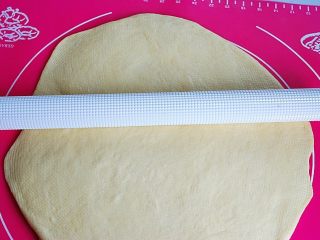 4、蜂蜜糯米小餐包,把面团取出，放案板上按扁，用排气棒将气体均匀的排出