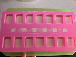 11、有内涵的麻将牌,用小刮刀刮平骰子的位置，刮去多余的巧克力溶液。这里有一个很重要的步骤，就是震模，硅胶模具下面垫一个硬板，双手托起后摔在桌子上，使之平稳落在桌子上，反复几次，如果没有震模或者震模不到位，做出来的麻将会因气泡等原因不平整。放入冰箱冷藏大概7-8分钟至表面冻硬