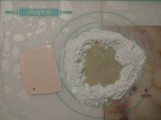 3、黑椒鸡肉披萨,粉和糖等倒入揉面垫上,中间扒窝,倒入水和酵母混合液。