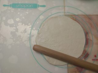 15、黑椒鸡肉披萨,取其中一份面团,擀成圆饼状。