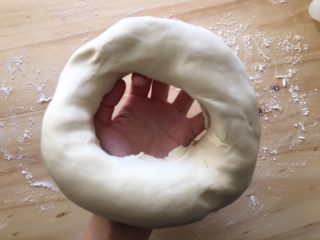 7、手工牛肉水饺,松弛好的面团取出，在案板上撒适量面粉，把面团中间抠个洞，从孔中间往外圈把孔撑大