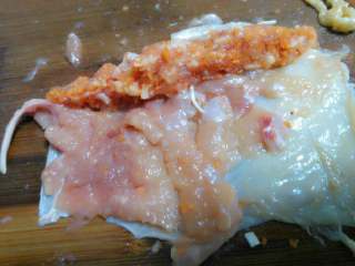 4、黄金鸡肉卷,把肉馅横向放鸡腿肉上，卷成一根条一趟。