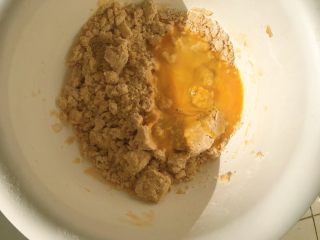 8、从小吃到大都吃不腻的黑芝麻桃酥,倒入搅拌均匀的鸡蛋液，继续用一次性手套混合在一起。