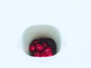 4、蔓越莓桑葚气泡水,榨汁杯里先放入蔓越莓果和桑葚,加入蜂蜜。