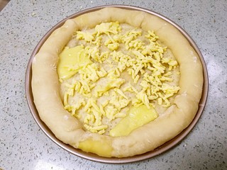 12、榴莲披萨,把烤好的面饼胚取出，烤箱继续预热200度。在饼胚上均匀撒一层马苏里拉芝士。（边上的芝士受热会有一点溢出，没关系的）