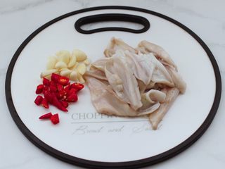 3、鲜鱿爆荷兰豆,把洗净的鱿鱼板，用刀切成大块后再改一下花刀，大蒜切片，小米辣切圈。