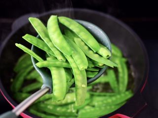 4、鲜鱿爆荷兰豆,锅中倒入适量的清水烧开，放入适量的盐和几滴食用油，把荷兰豆进行焯水，变色捞出过冷水备用。