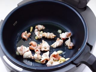 6、鲜鱿爆荷兰豆,智能炒菜机里，先倒入花生油和大蒜片，再放入焯好的鱿鱼。