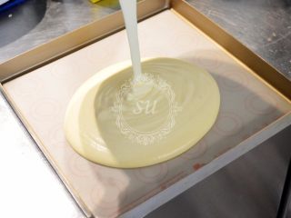 6、超详细图解——小四卷+日式豆乳盒子蛋糕,混合好的面糊倒入烤盘中，我在烤盘底部铺了一块玻璃纤维垫，方便脱模。从大约20公分高度处从烤盘中心倒入