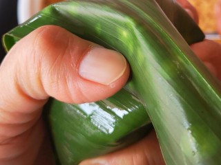 19、大肉粽,将粽叶盖下来，左手大拇指和食指分别按住两边，用右手将多余粽叶折至左手拇指方向，再用线捆起来(由于一人完成，拍不了照????)