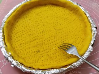 8、南瓜虾仁培根披萨,烤箱预热180度5分钟。用叉子在面皮上扎一些孔，入烤箱180度烤5分钟