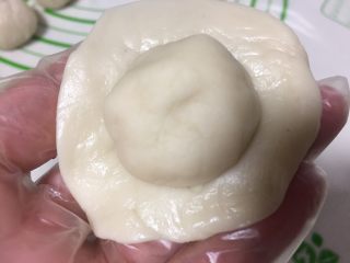 6、紫薯蛋黄酥,取一个油皮捏成圆片中间放上一个油酥。
