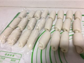 10、紫薯蛋黄酥,自下而上推卷起来，全部擀好收口朝下，盖保鲜膜松弛15分钟。