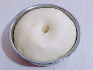 8、日式炼乳蔓越莓面包,发酵好的面团是原来的两倍大，用手指按一下，不回缩即为发酵完成！取出揉圆排气，盖上保鲜膜醒10分钟！