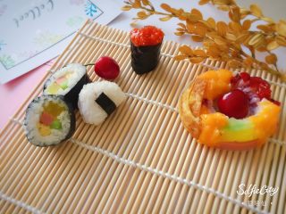 7、寿司????版的欢乐颂五美,米饭捏一团，中间塞入章鱼粒，捏成三角形，然后把海苔剪成长方形，把饭团底部包半圈，章鱼三角形饭团就做好了